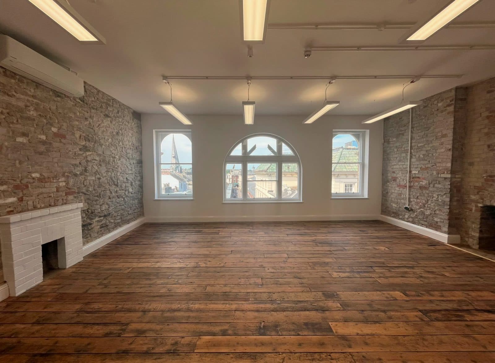 Inside The Loft: exposed brick walls, original wooden floorboards and tall arched windows looking out over Barnstaple rooftops.